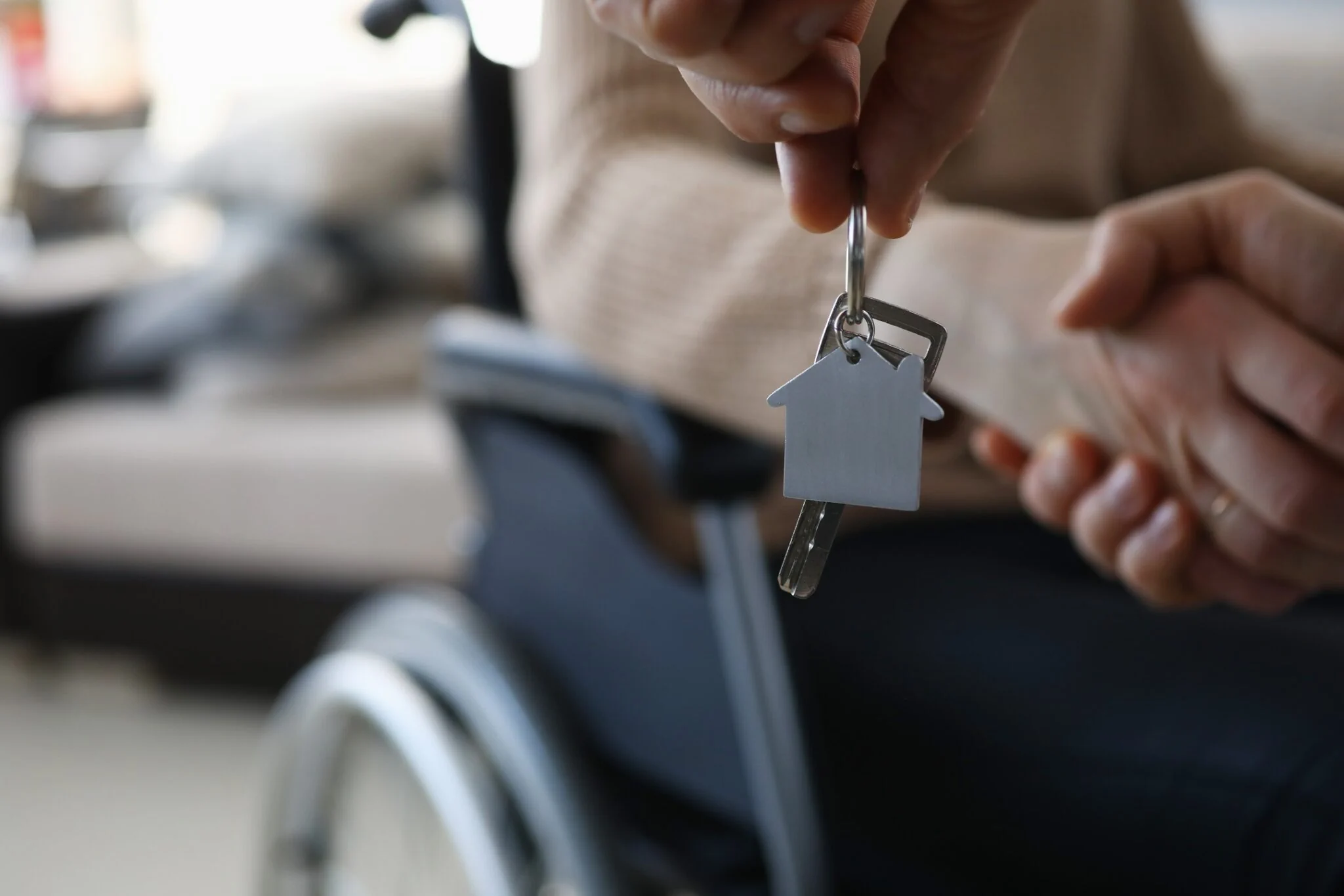 Assisted Living Investment Property Keys UK House keys with home shaped keyring exchanged beside wheelchair for assisted living investments and UK property investment guide