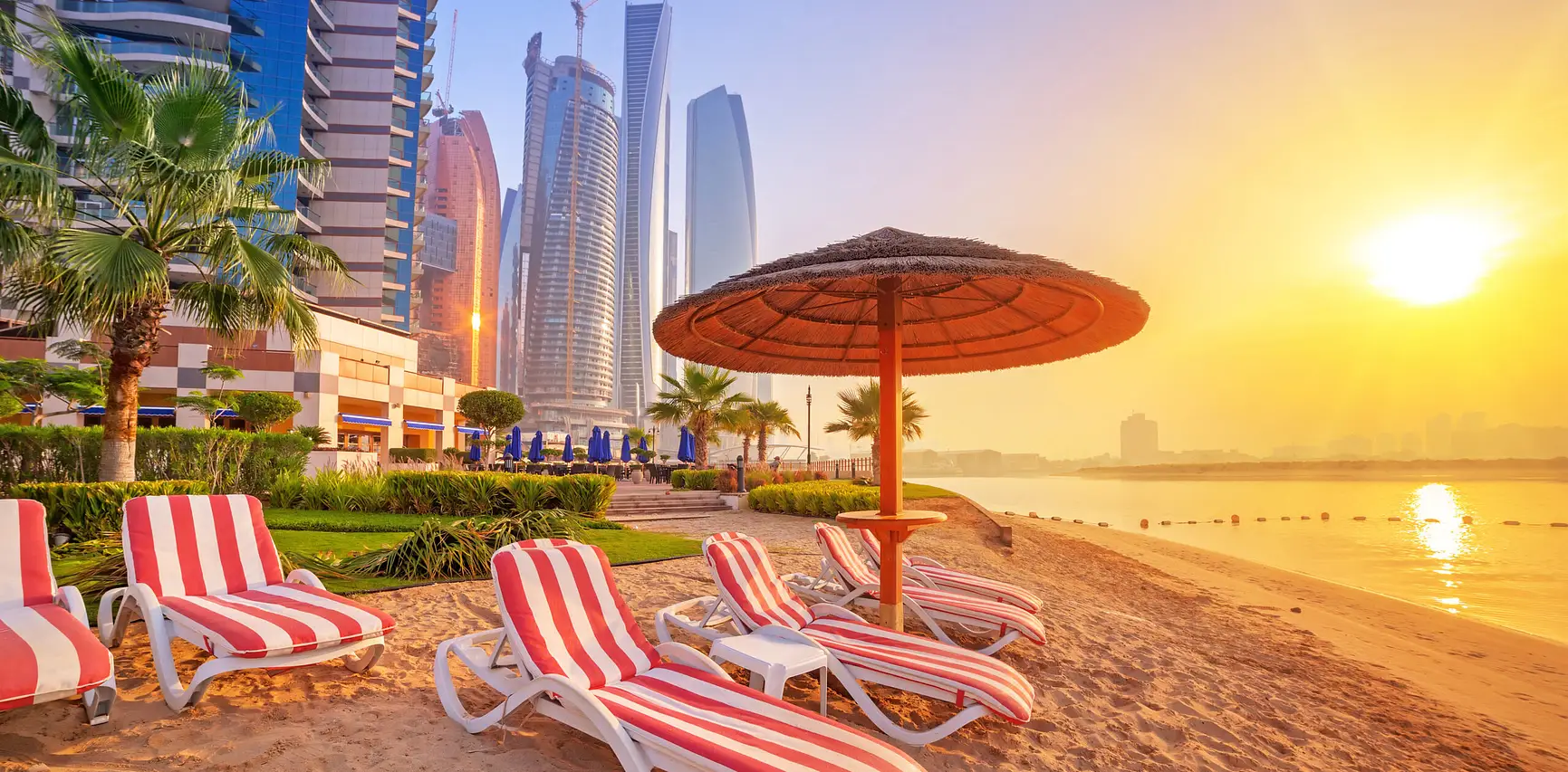 Abu Dhabi beachfront with sun loungers and skyline representing luxury property investment and lifestyle appeal in UAE