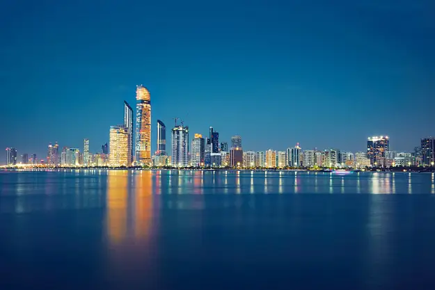 Abu Dhabi skyline at night with waterfront reflections representing ownership framework for overseas property investors in UAE
