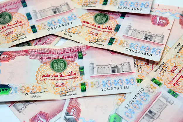 UAE dirham banknotes scattered representing key financial considerations for Dubai property investment and currency exposure