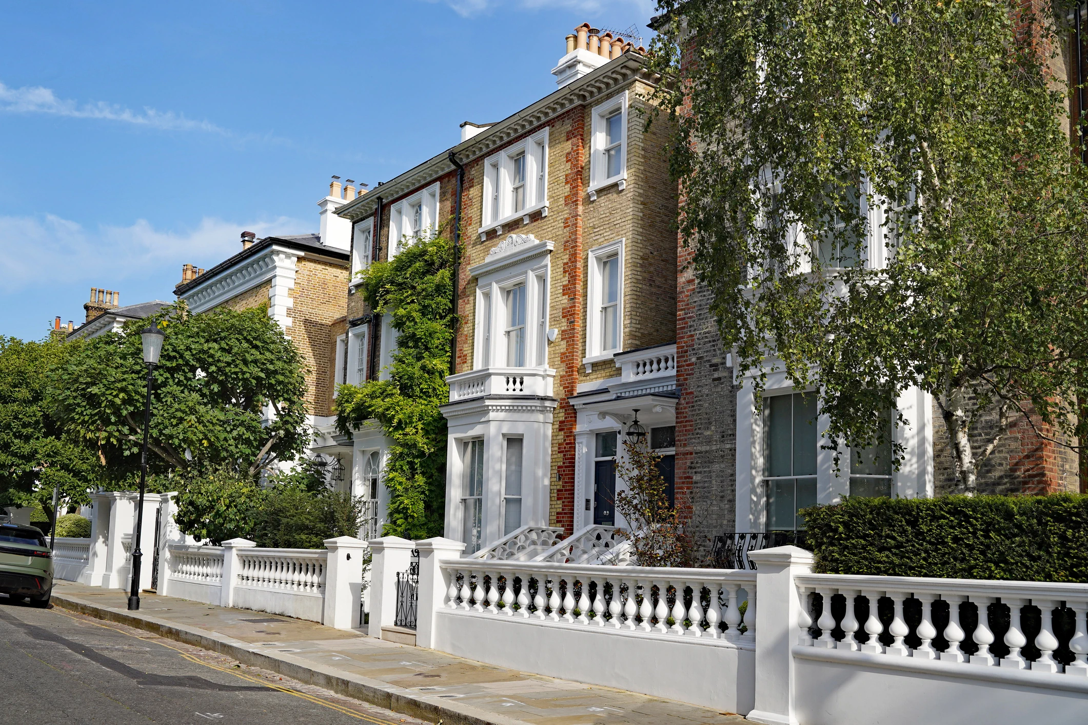 Elegant UK terraced houses with greenery and white railings representing supported housing investment opportunities and residential stability