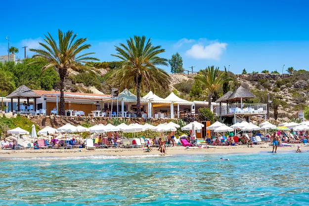 Cyprus beach with palm trees and seaside cafes highlighting visa and residency considerations for property investors