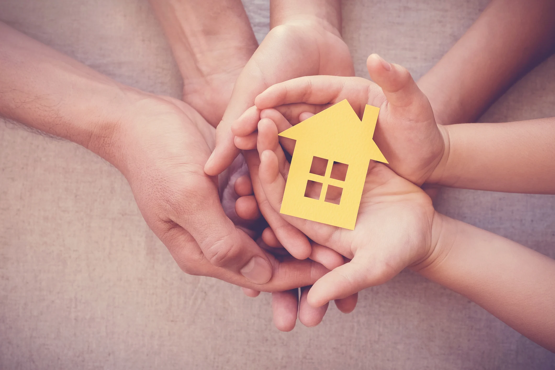 Hands holding a house symbol representing family security and the long term benefits of UK property investment