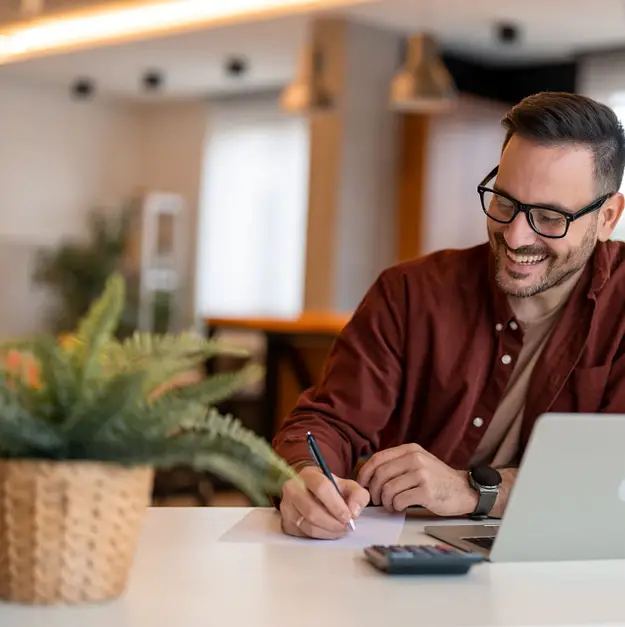 Man reviewing paperwork at desk with laptop representing specialist supported housing investments and long term income planning