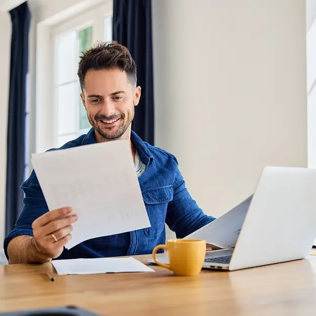 Man reviewing documents at laptop representing assisted living investments with 365 Invest and hands off property income planning