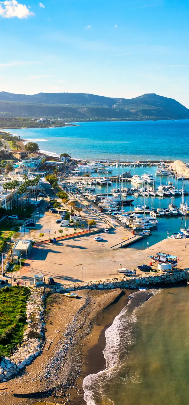 Aerial view of Cyprus marina with yachts, coastal town and sandy beach highlighting prime property investment opportunities by the sea