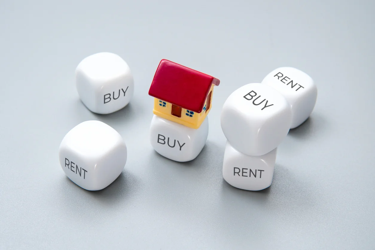 Buy or rent decision concept with house model on dice illustrating buy to let property investment choices and strategy