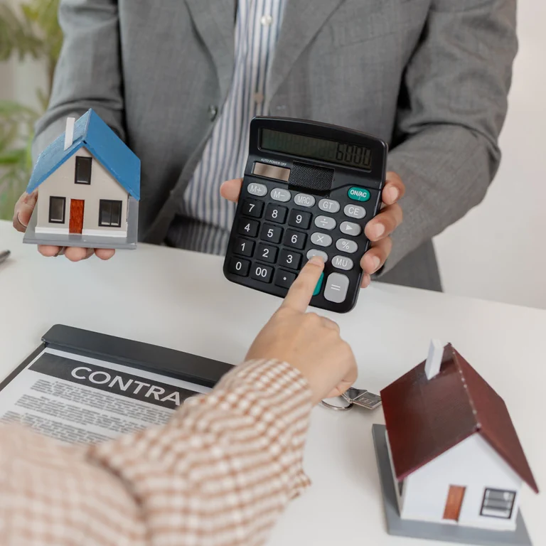 Person using calculator with model houses and contract illustrating informed UK property investment decisions and financial planning process