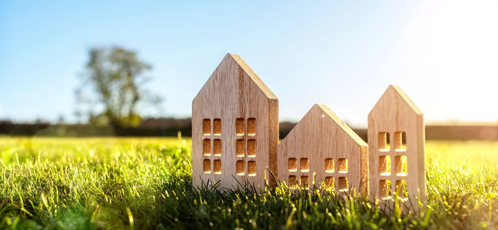 Wooden house models on grass representing assisted living investments with 365 Invest for hands off property income opportunities